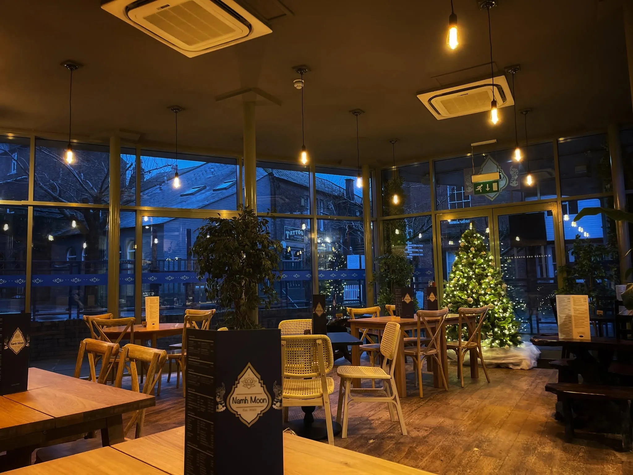 Warm lights above the wooden tables in Namh Moon's glass-fronted dining room